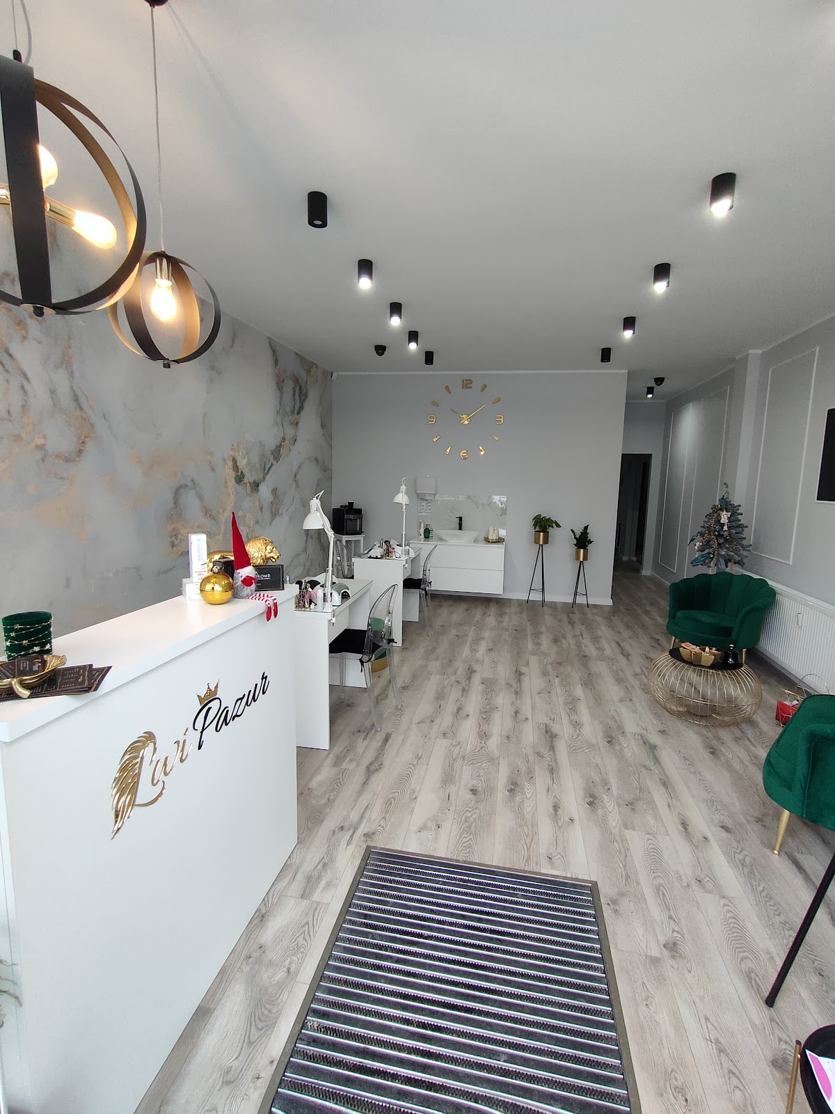 Recepcja salonu Lwi Pazur ze złotym logo i zielonymi fotelami